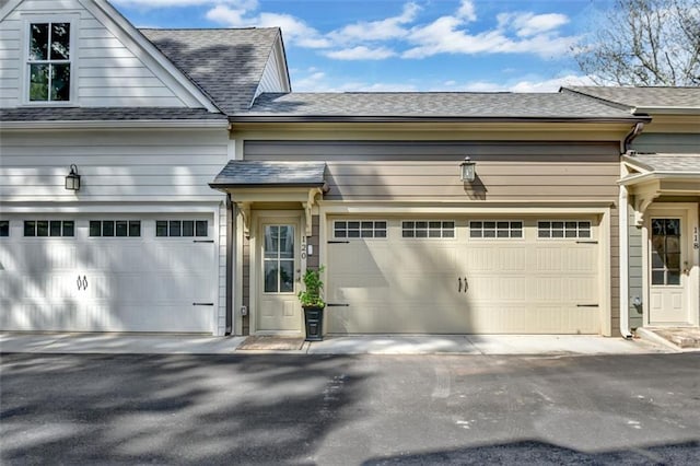 view of front facade featuring driveway, a shingled roof, and a garage