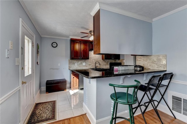 6118 Queen Anne Ct, Norcross, GA 30093 - kitchen featuring decorative backsplash, a kitchen breakfast bar, ceiling fan, a peninsula, and a textured ceiling
