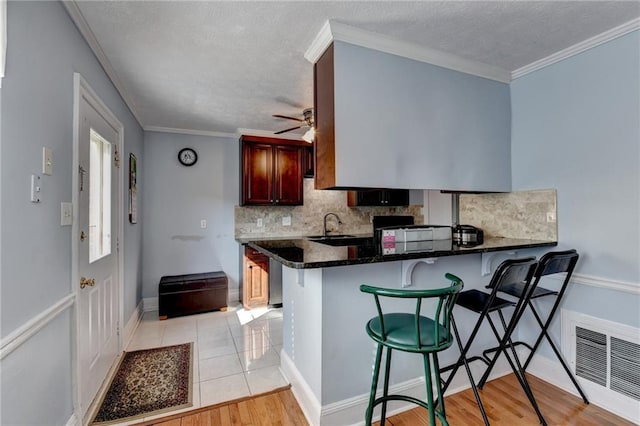 6118 Queen Anne Ct, Norcross, GA 30093 - kitchen featuring tasteful backsplash, a kitchen bar, a peninsula, a ceiling fan, and light wood finished floors