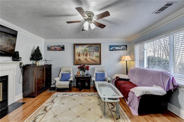 6118 Queen Anne Ct, Norcross, GA 30093 - sitting room featuring wood finished floors, ceiling fan, a fireplace with flush hearth, crown molding, and a textured ceiling