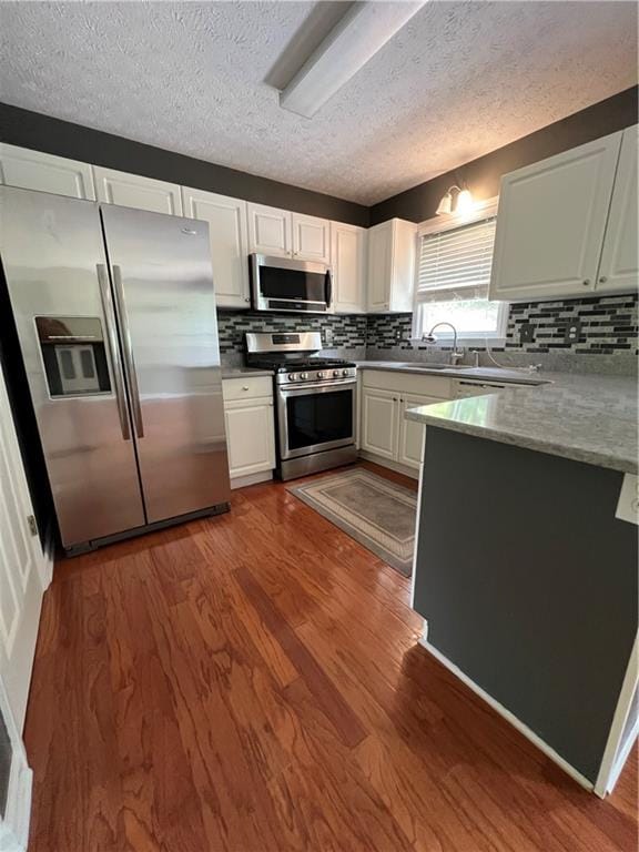 11 Seabreeze Way, Dawsonville, GA 30534 - kitchen with appliances with stainless steel finishes, a peninsula, white cabinetry, dark wood finished floors, and a textured ceiling
