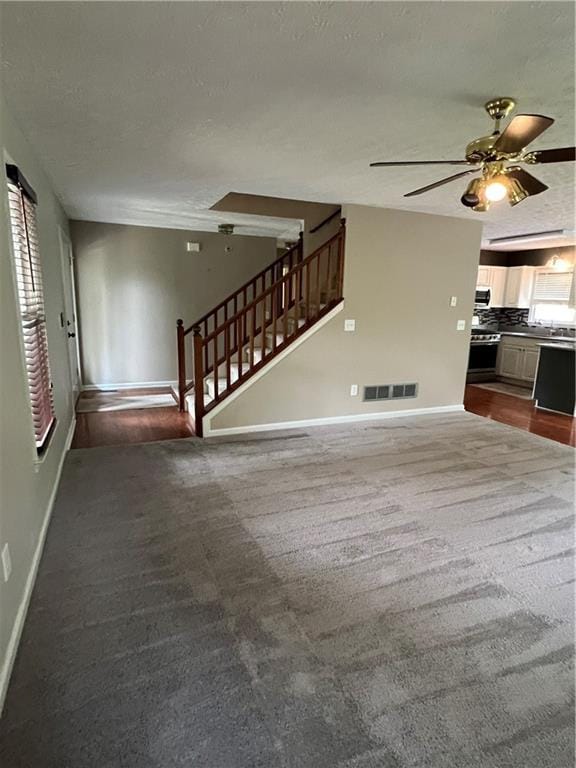 11 Seabreeze Way, Dawsonville, GA 30534 - unfurnished living room featuring carpet flooring, ceiling fan, stairs, and a textured ceiling