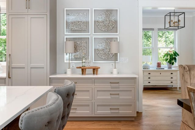 interior space with light stone countertops, pendant lighting, light hardwood / wood-style flooring, and an inviting chandelier