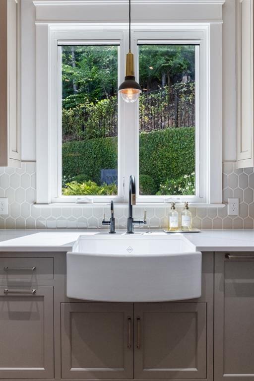 interior details with backsplash, gray cabinets, sink, and decorative light fixtures