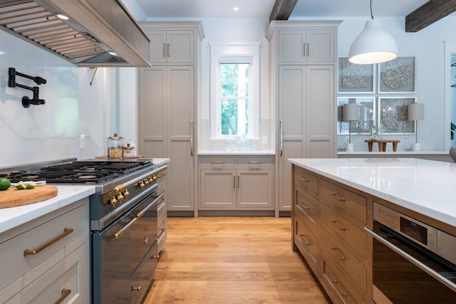 kitchen featuring light hardwood / wood-style flooring, premium range hood, decorative light fixtures, gray cabinets, and high end range