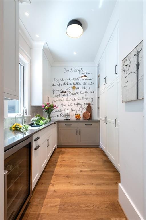 mudroom with light hardwood / wood-style floors, sink, and beverage cooler