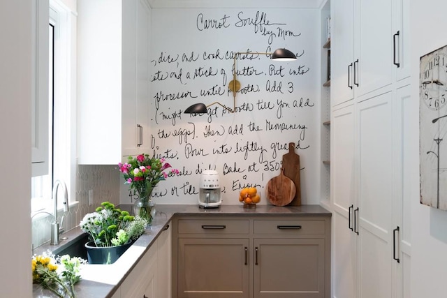 bar featuring white cabinets and sink