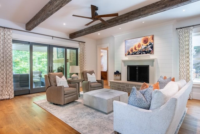 living room featuring beam ceiling, ceiling fan, a healthy amount of sunlight, and light hardwood / wood-style floors