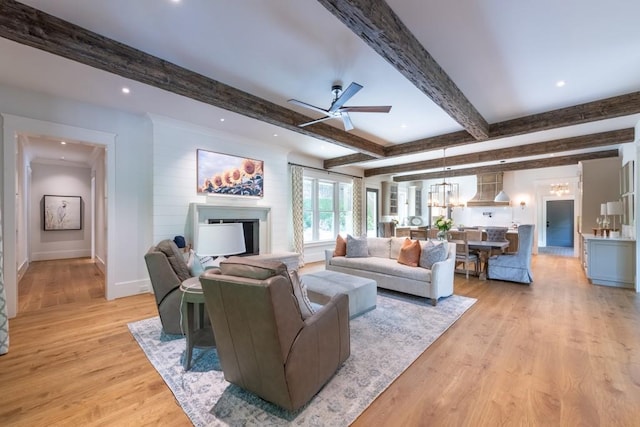 living room featuring beamed ceiling, ceiling fan, and light hardwood / wood-style flooring