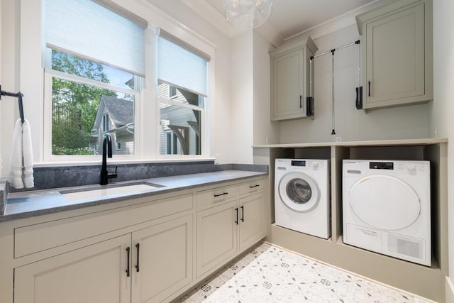 clothes washing area featuring washing machine and clothes dryer, sink, cabinets, and ornamental molding