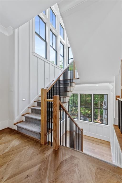 stairs featuring a wealth of natural light, crown molding, a towering ceiling, and parquet flooring