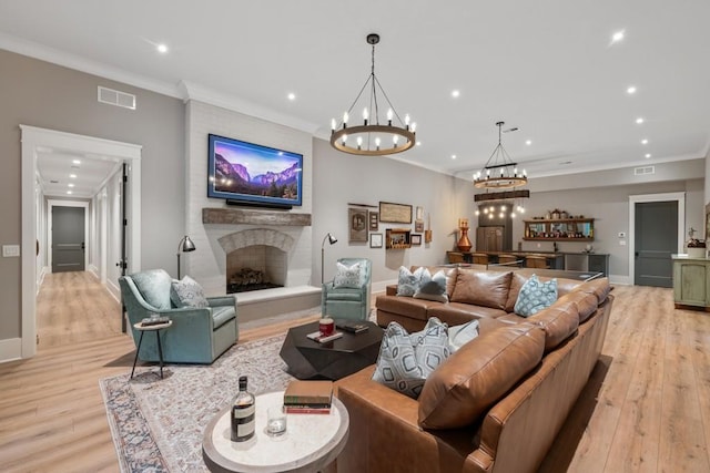 living room with a large fireplace, ornamental molding, and light wood-type flooring