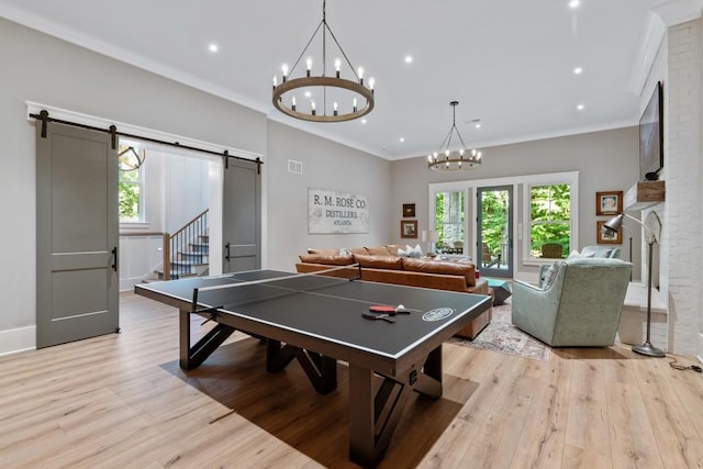 rec room featuring a barn door, crown molding, and light hardwood / wood-style flooring