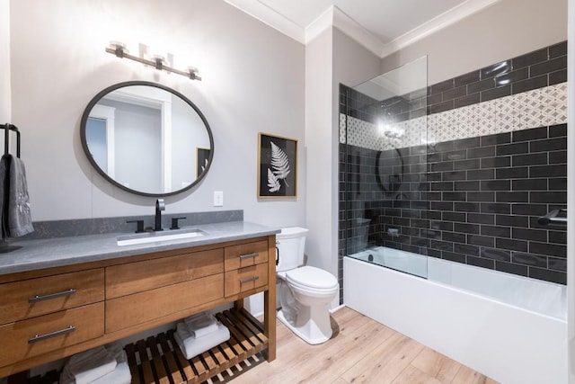 full bathroom featuring ornamental molding, vanity, hardwood / wood-style floors, toilet, and tiled shower / bath