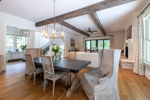 dining room with ceiling fan with notable chandelier, a healthy amount of sunlight, beam ceiling, and light hardwood / wood-style flooring