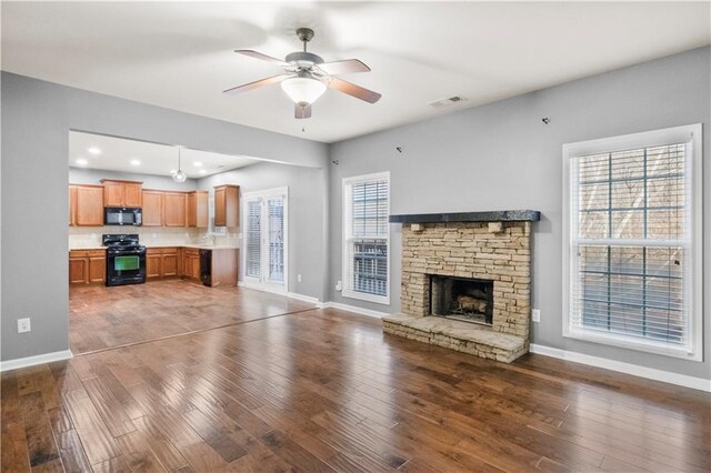 unfurnished living room with a healthy amount of sunlight, dark hardwood / wood-style flooring, and a fireplace