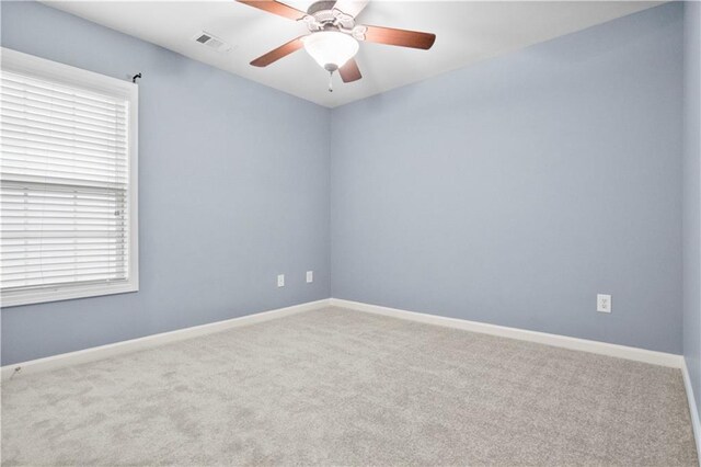 spare room with light colored carpet, a wealth of natural light, and ceiling fan