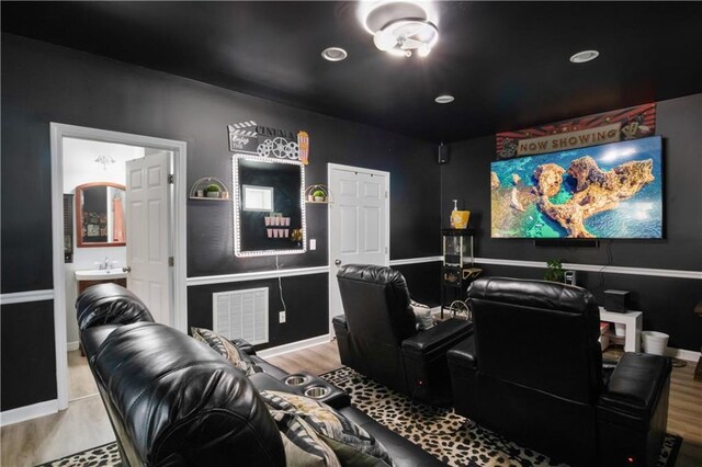 home theater room with light hardwood / wood-style floors and sink