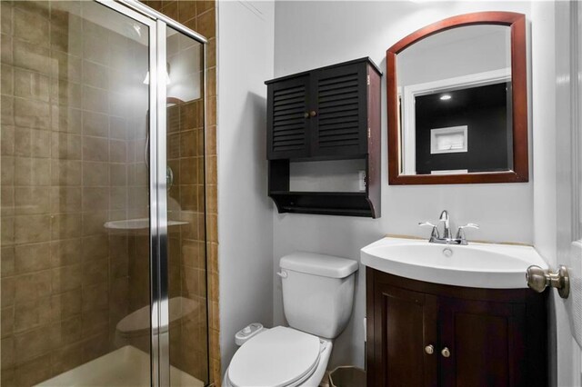 bathroom with vanity, toilet, and a shower with shower door