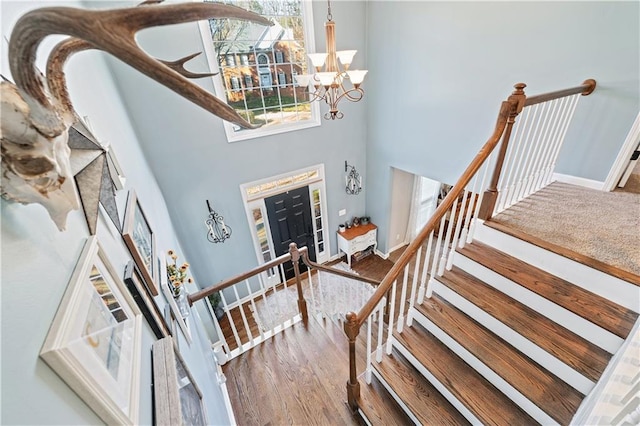 foyer entrance featuring wood-type flooring, a towering ceiling, and a notable chandelier