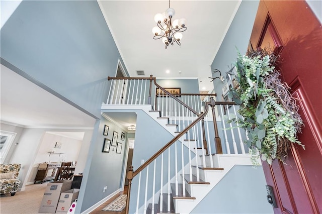 stairway with ornamental molding, a chandelier, carpet floors, and a high ceiling