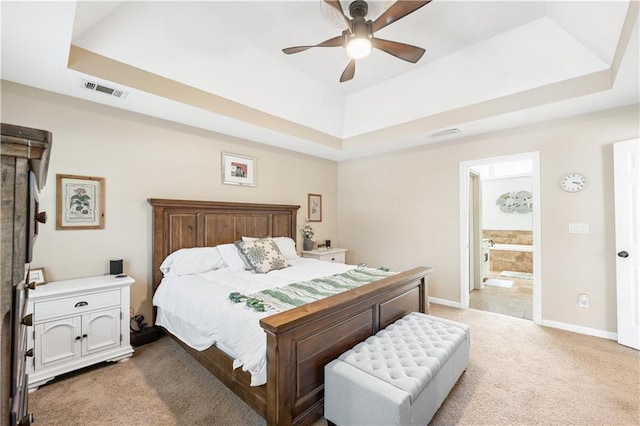 bedroom featuring light carpet, a tray ceiling, and ceiling fan