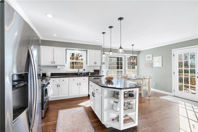 kitchen featuring decorative light fixtures, plenty of natural light, appliances with stainless steel finishes, a kitchen island, and white cabinets