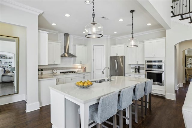 3005 Evelyn Ln, Alpharetta, GA 30004 - kitchen featuring appliances with stainless steel finishes, wall chimney exhaust hood, arched walkways, ornamental molding, and a kitchen bar