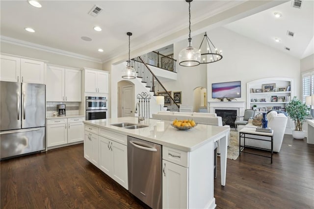 3005 Evelyn Ln, Alpharetta, GA 30004 - kitchen with appliances with stainless steel finishes, a glass covered fireplace, light countertops, a center island with sink, and white cabinetry