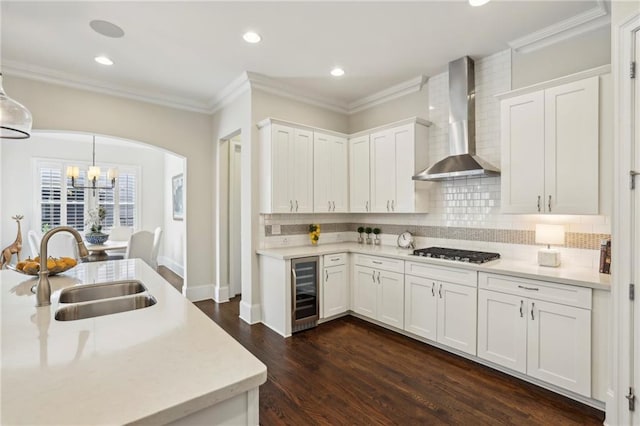 3005 Evelyn Ln, Alpharetta, GA 30004 - kitchen featuring wall chimney range hood, beverage cooler, stainless steel gas stovetop, light countertops, and arched walkways