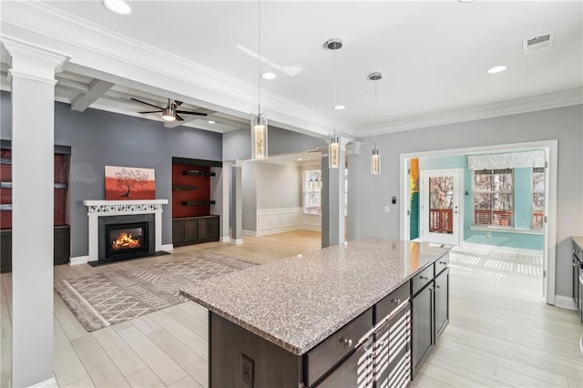 kitchen with a center island, hanging light fixtures, light hardwood / wood-style flooring, beamed ceiling, and light stone countertops