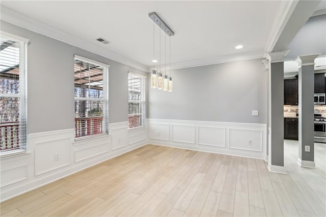 unfurnished dining area featuring crown molding, light hardwood / wood-style floors, and ornate columns