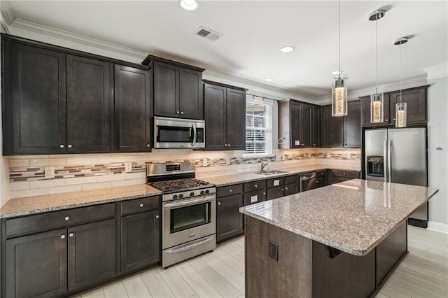 kitchen with dark brown cabinetry, decorative light fixtures, a kitchen island, stainless steel appliances, and backsplash