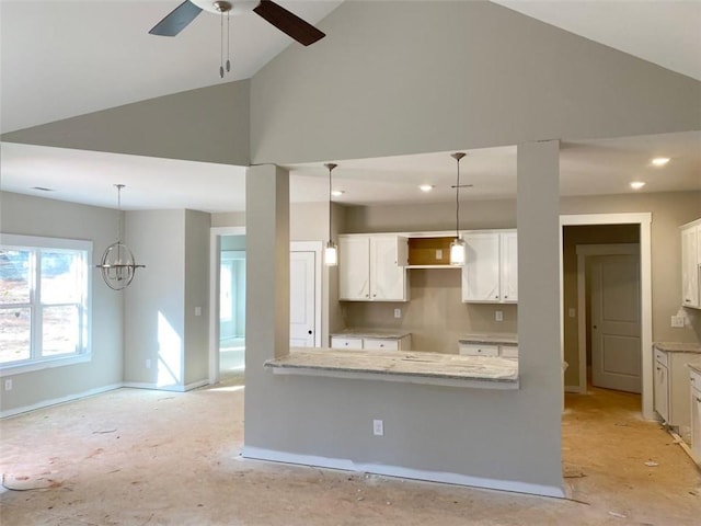 kitchen featuring light stone counters, white cabinets, and hanging light fixtures