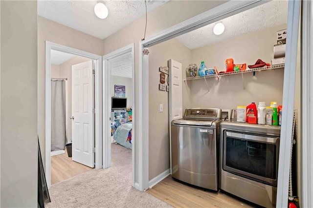 4161 Magnolia Glen Walk, Norcross, GA 30093 - laundry room featuring washer and clothes dryer, a textured ceiling, baseboards, light wood finished floors, and light carpet