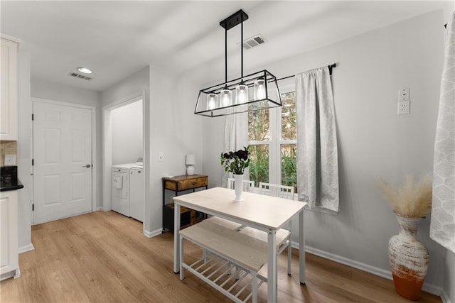 dining space featuring washer and clothes dryer, light wood-type flooring, visible vents, and baseboards