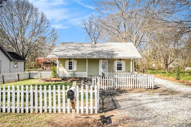 bungalow featuring a fenced front yard, covered porch, metal roof, and driveway