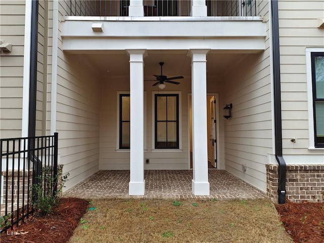 view of exterior entry featuring a ceiling fan and a balcony