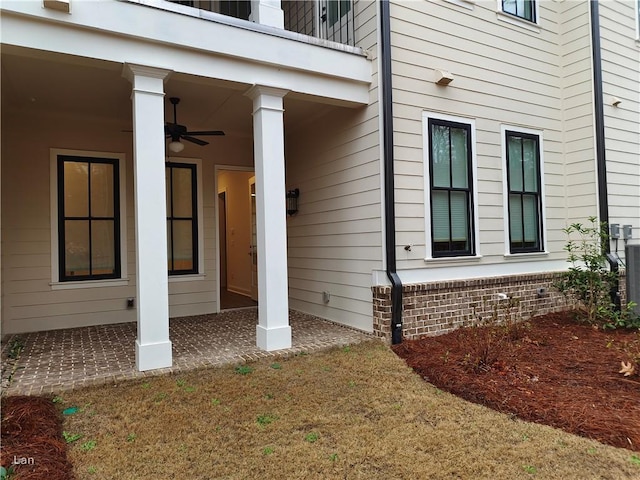 entrance to property with ceiling fan and brick siding