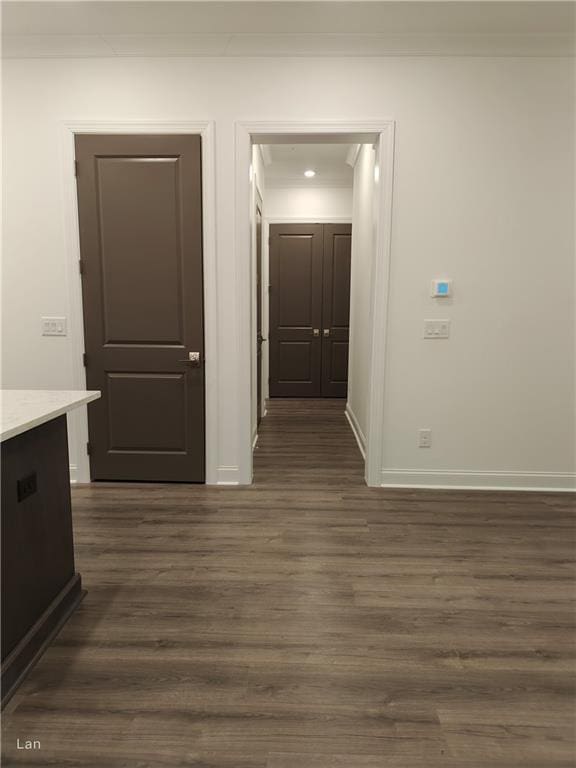 hallway featuring ornamental molding, baseboards, and dark wood-style floors