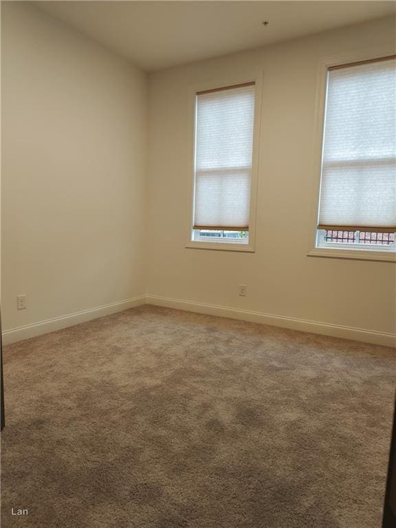 spare room featuring carpet floors and baseboards