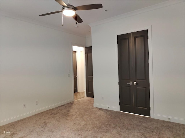 unfurnished bedroom with ornamental molding, carpet, a ceiling fan, and baseboards