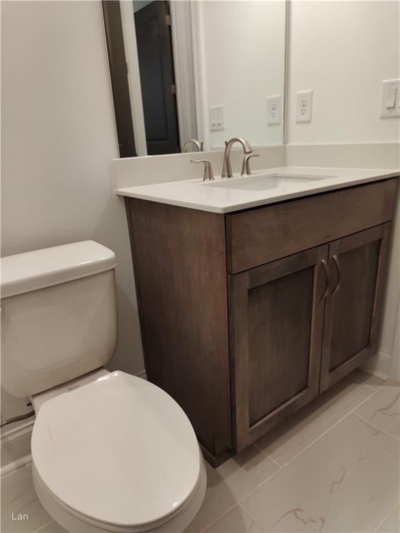 bathroom with toilet, marble finish floor, and vanity