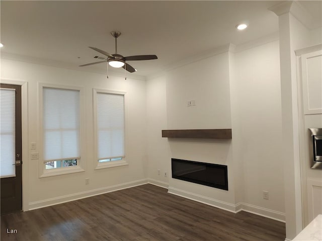 unfurnished living room with baseboards, dark wood-style flooring, crown molding, and a glass covered fireplace