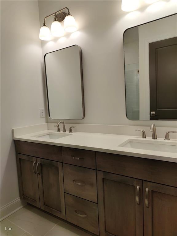 full bath with double vanity, a sink, and baseboards