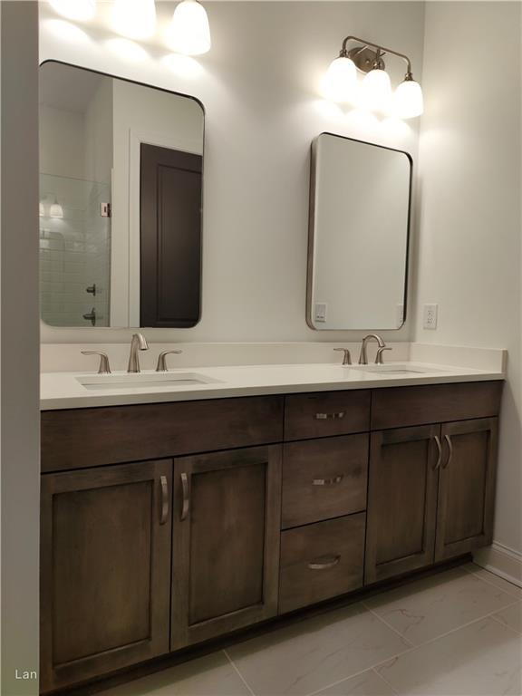 full bathroom with double vanity, a sink, and a shower with shower door