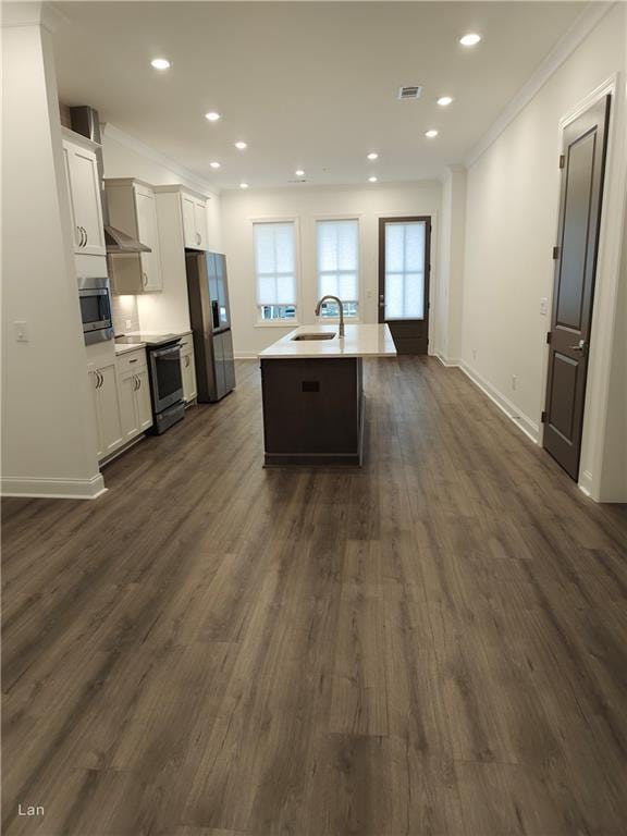 kitchen featuring crown molding, stainless steel appliances, a kitchen island with sink, a sink, and white cabinetry