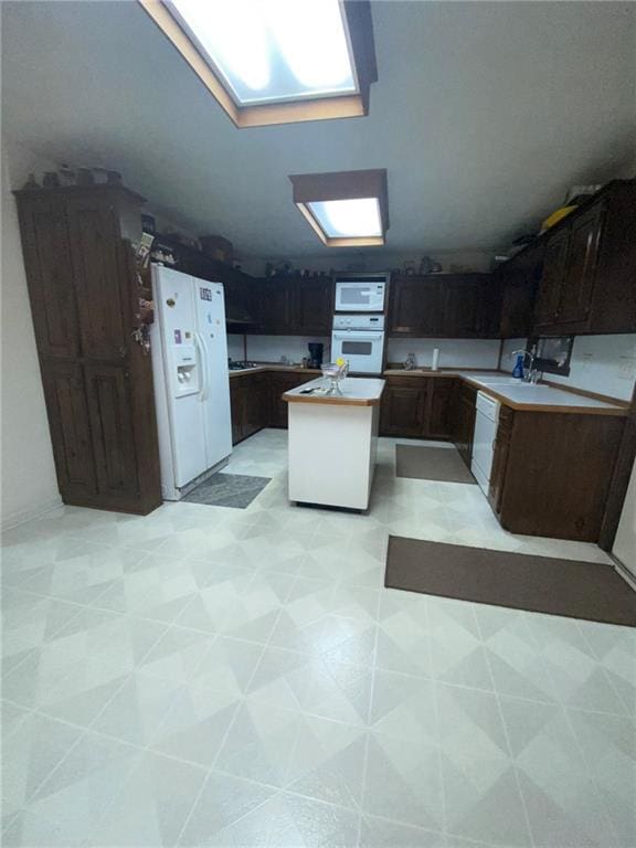 kitchen with light tile patterned flooring, dark brown cabinets, and white appliances