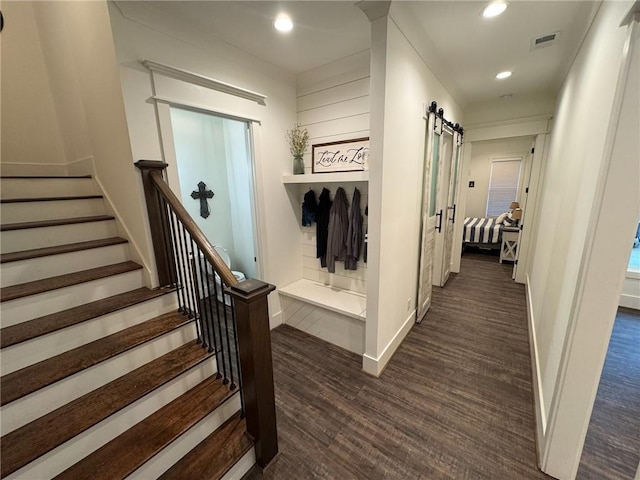 hall with a barn door and dark hardwood / wood-style flooring