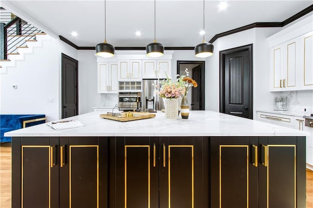 kitchen with stainless steel appliances, a kitchen island, light stone countertops, white cabinets, and pendant lighting